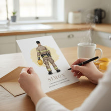 A person is writing a card for someone named Simon, congratulating him on becoming a firefighter.