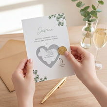 A person's hands holding a card with a heart-shaped design and text, with a gold coin inserted into the card.