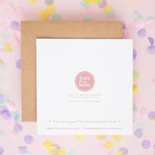 a white card with text and a pink logo, placed on a background of colorful confetti.